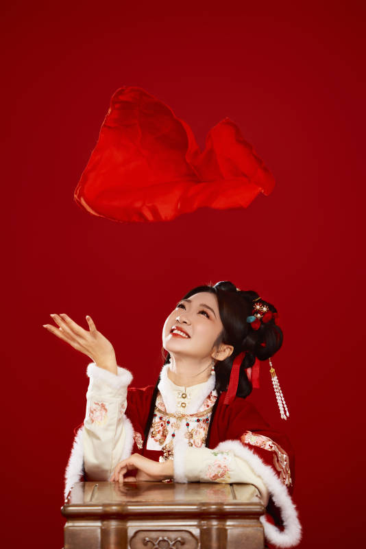 喜庆红色背景下身穿中国汉服的年轻女性