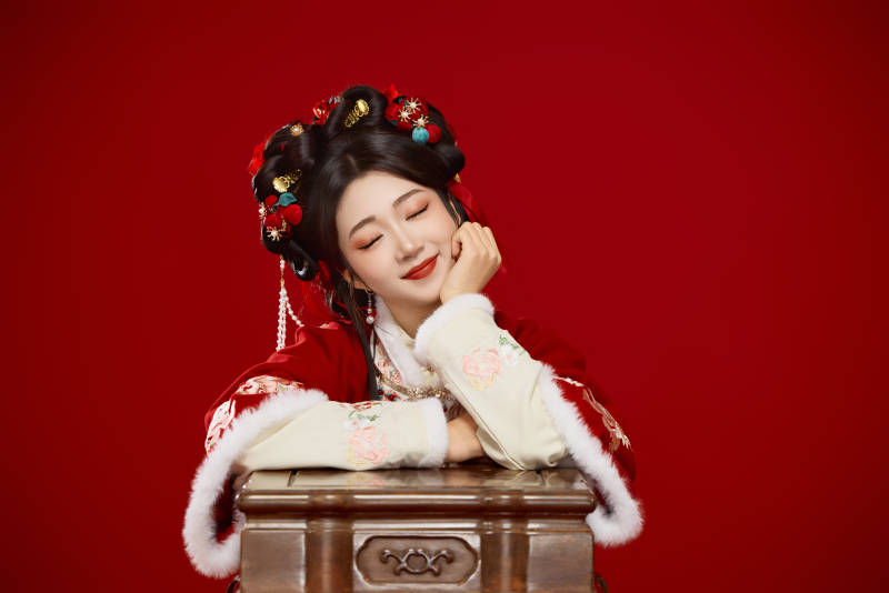 喜庆红色背景下身穿中国汉服的年轻女性