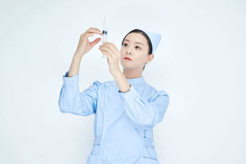 穿护士服戴口罩手执针筒的年轻女护士