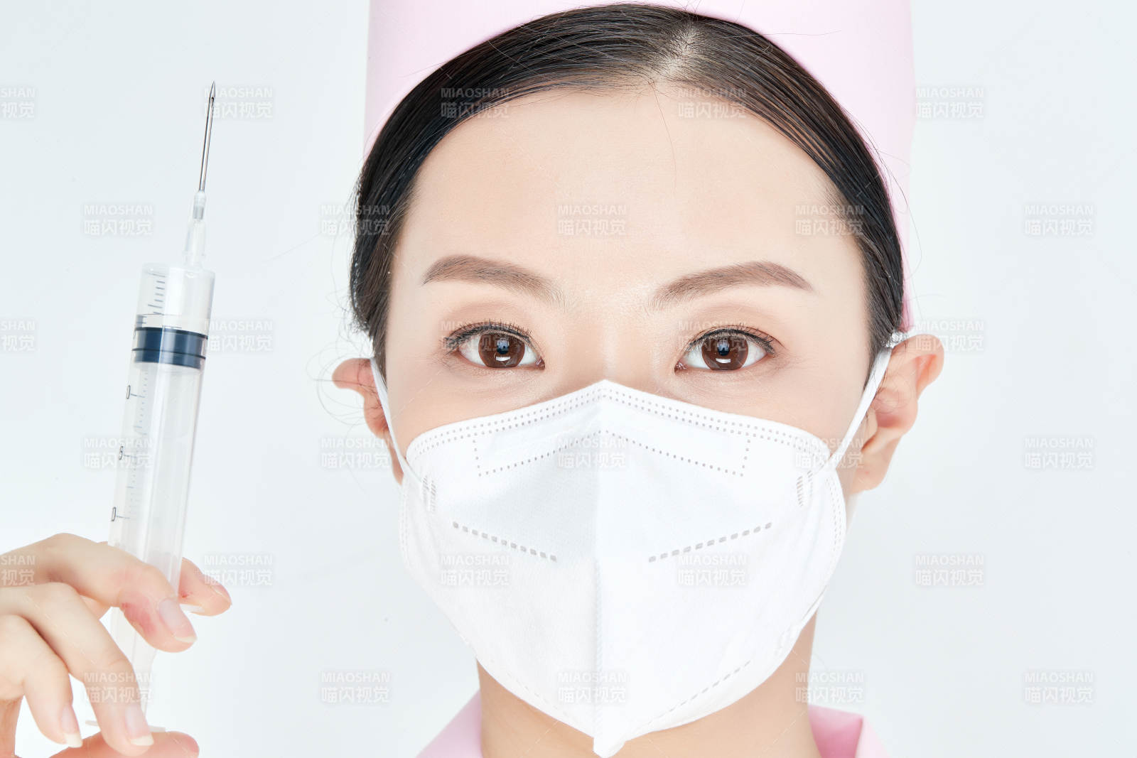 穿护士服戴口罩手执针筒的年轻女护士图片