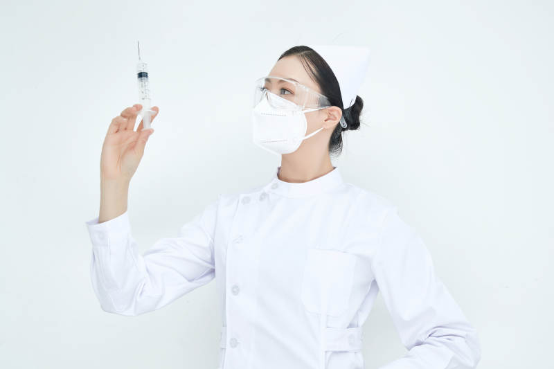 穿护士服戴口罩手执针筒的年轻女护士