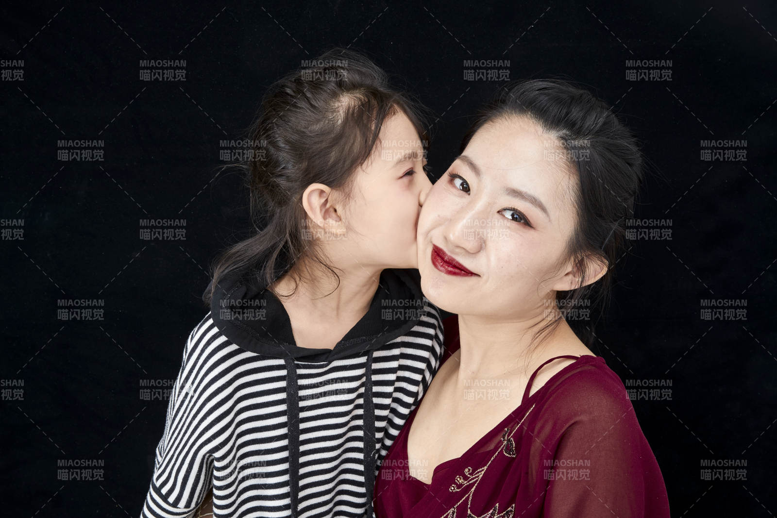 黑色背景的美丽妈妈与可爱女儿亲子人像
