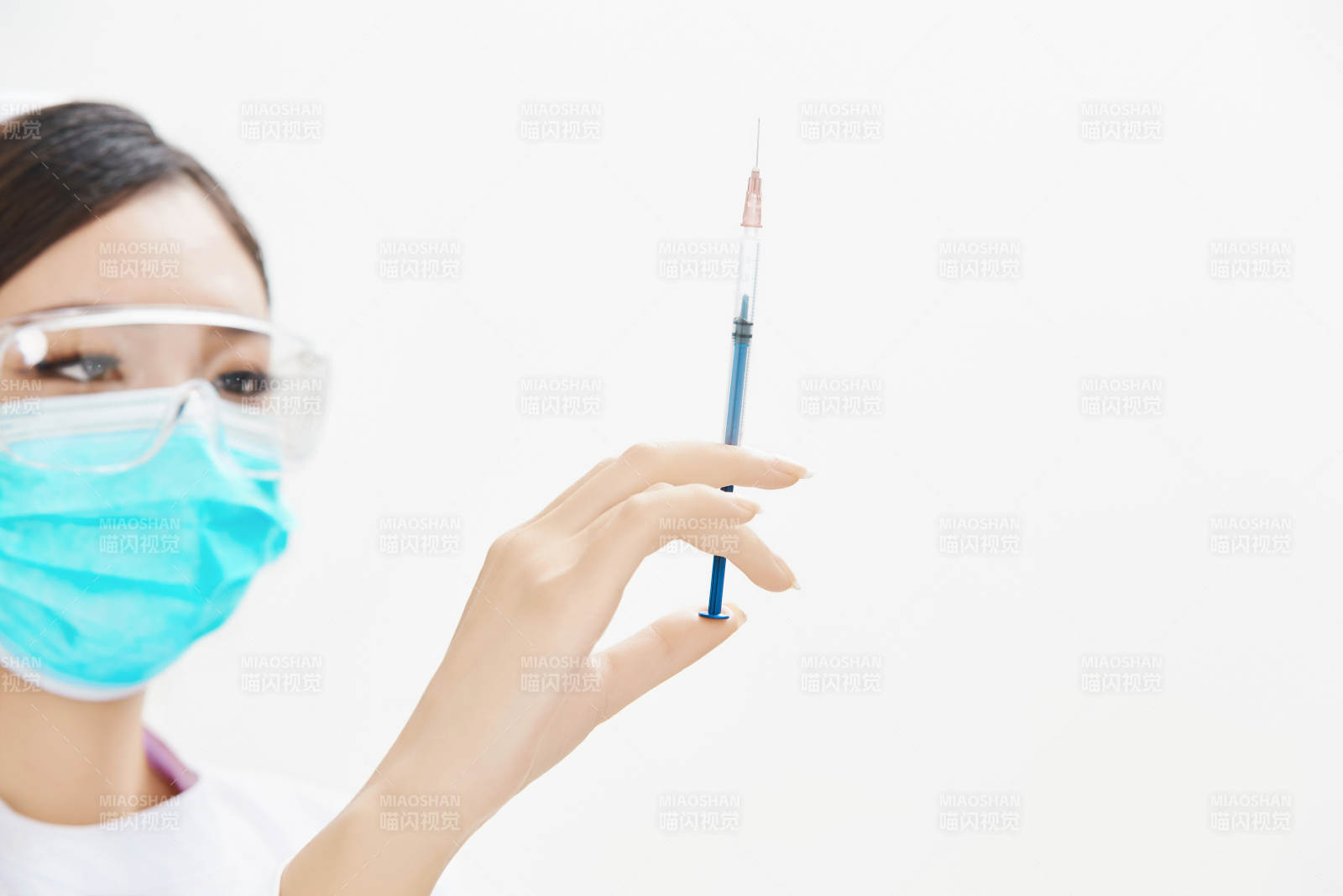 穿护士服戴口罩手执针筒的年轻女护士