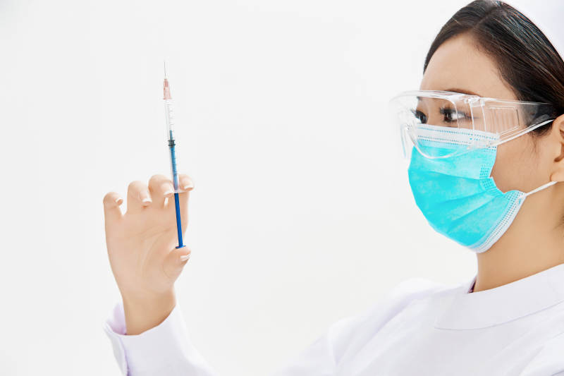 穿护士服戴口罩手执针筒的年轻女护士