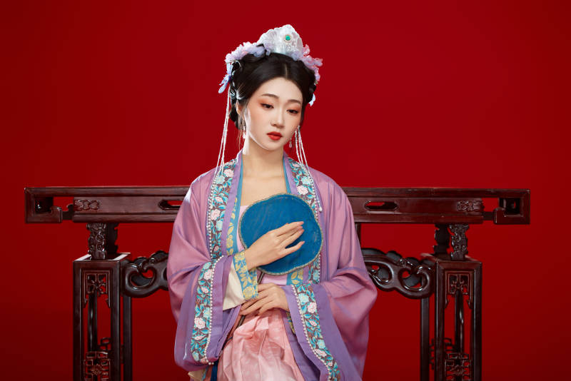 红色背景下身穿中国明朝簪花发饰汉服的美女