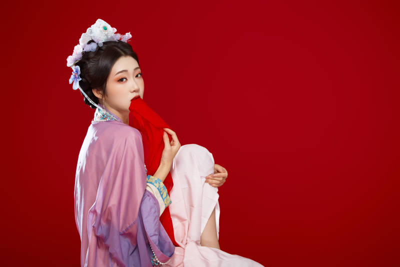 红色背景下身穿中国明朝簪花发饰汉服的美女