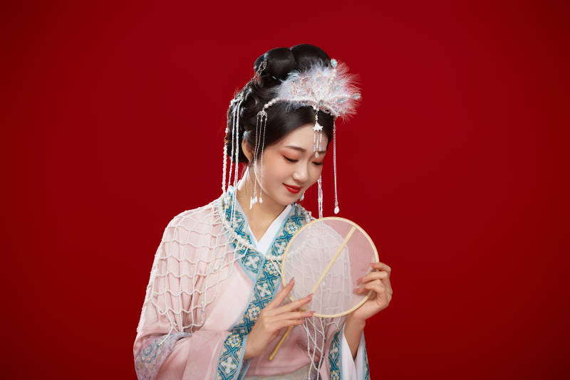 红色背景下身穿中国明朝簪花发饰汉服的美女