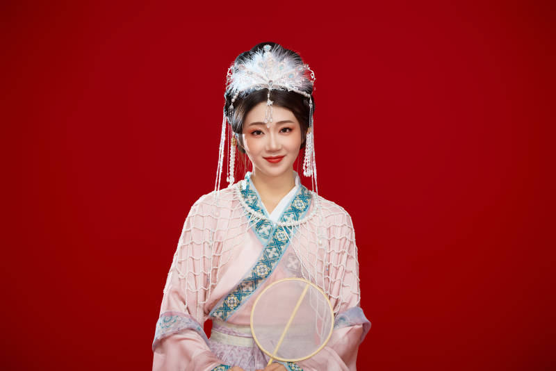 红色背景下身穿中国明朝簪花发饰汉服的美女