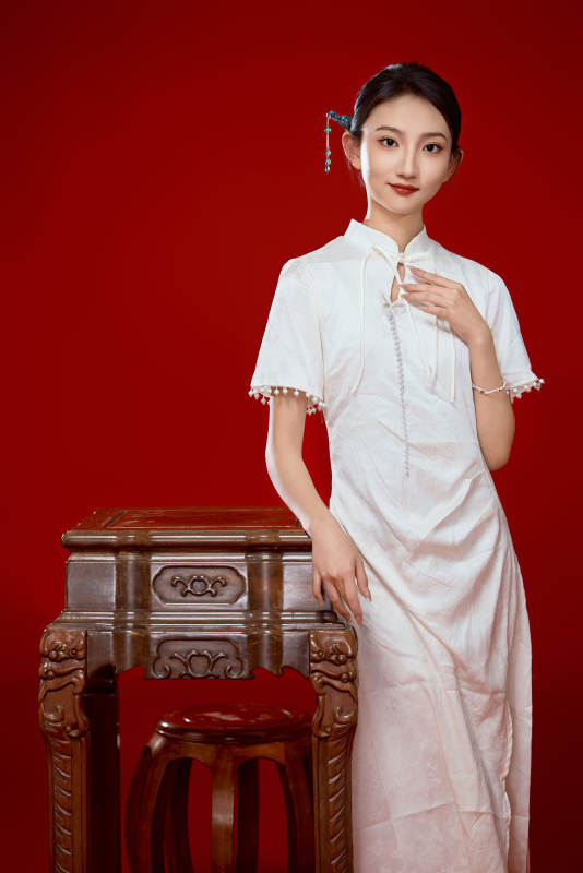 红色背景下穿着中式传统旗袍的美丽少女
