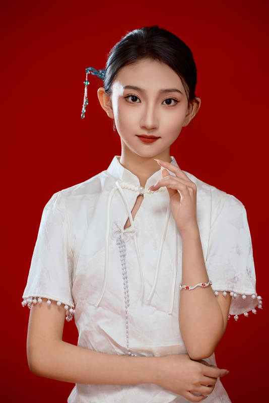 红色背景下穿着中式传统旗袍的美丽少女