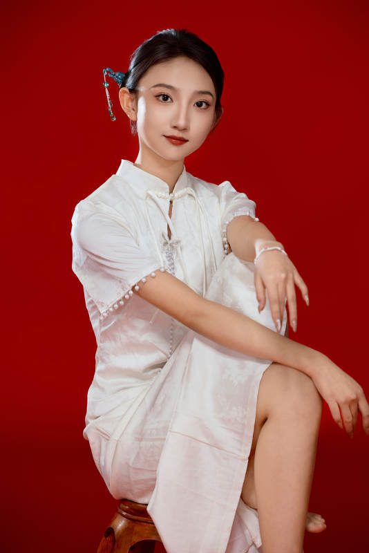 红色背景下穿着中式传统旗袍的美丽少女