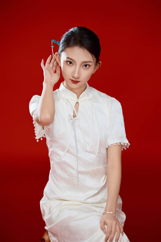 红色背景下穿着中式传统旗袍的美丽少女