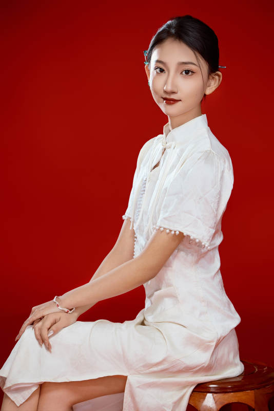 红色背景下穿着中式传统旗袍的美丽少女