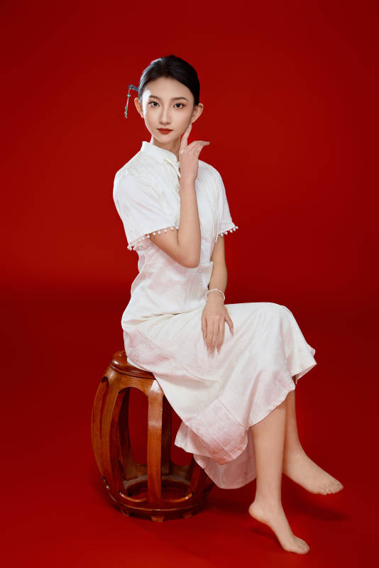 红色背景下穿着中式传统旗袍的美丽少女