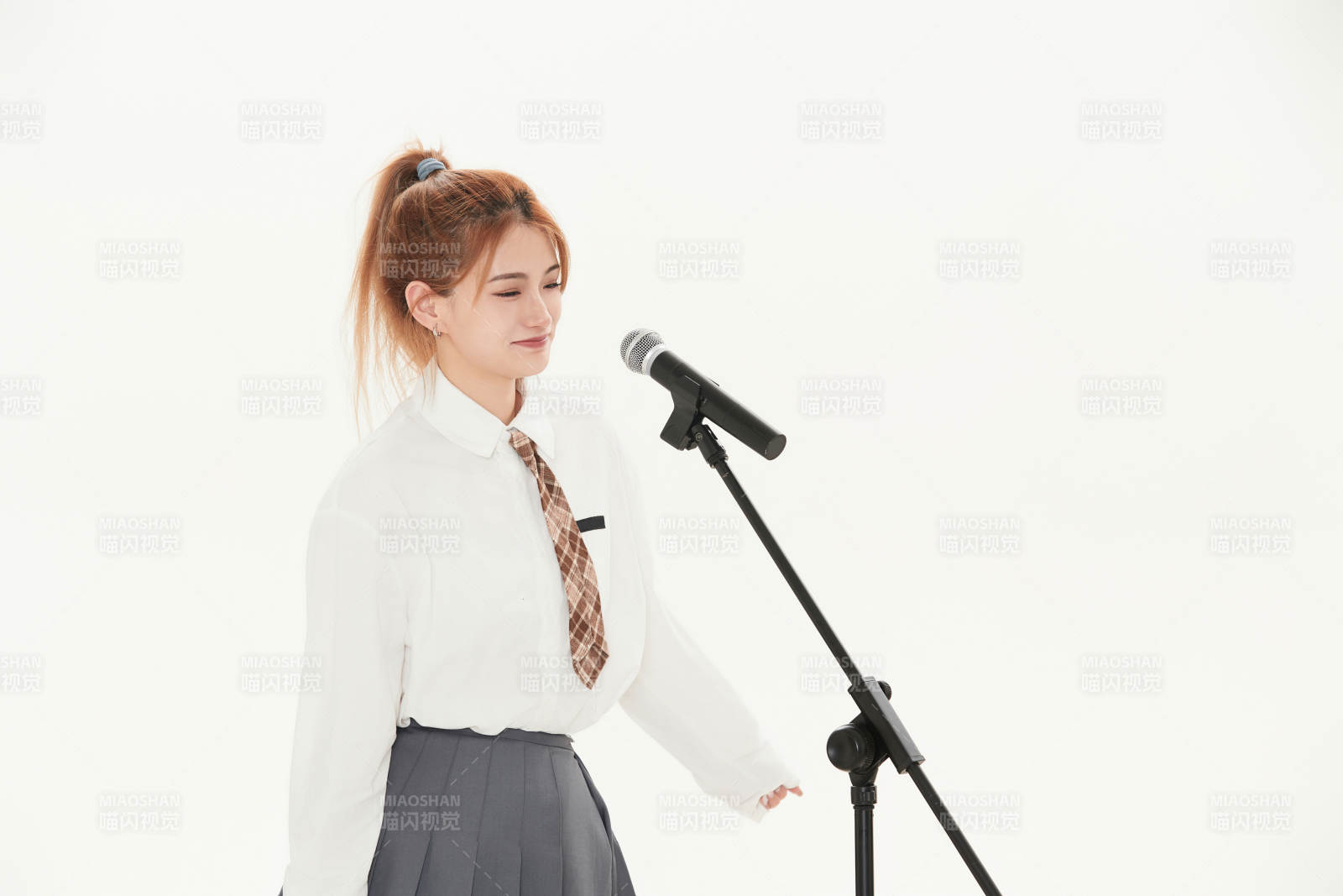 白色背景下站在麦克风前唱歌的亚洲女性