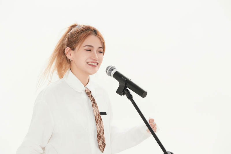 白色背景下站在麦克风前唱歌的亚洲女性