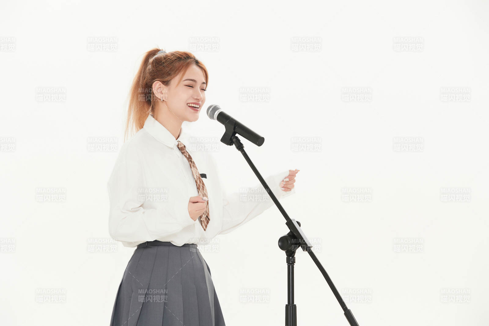 白色背景下站在麦克风前唱歌的亚洲女性