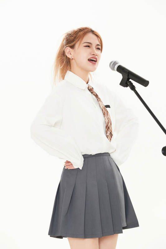 白色背景下站在麦克风前唱歌的亚洲女性