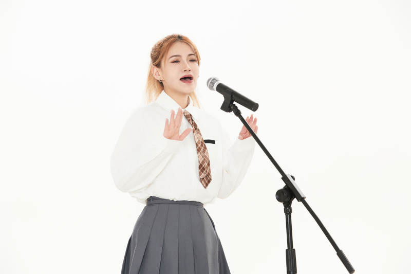 白色背景下站在麦克风前唱歌的亚洲女性