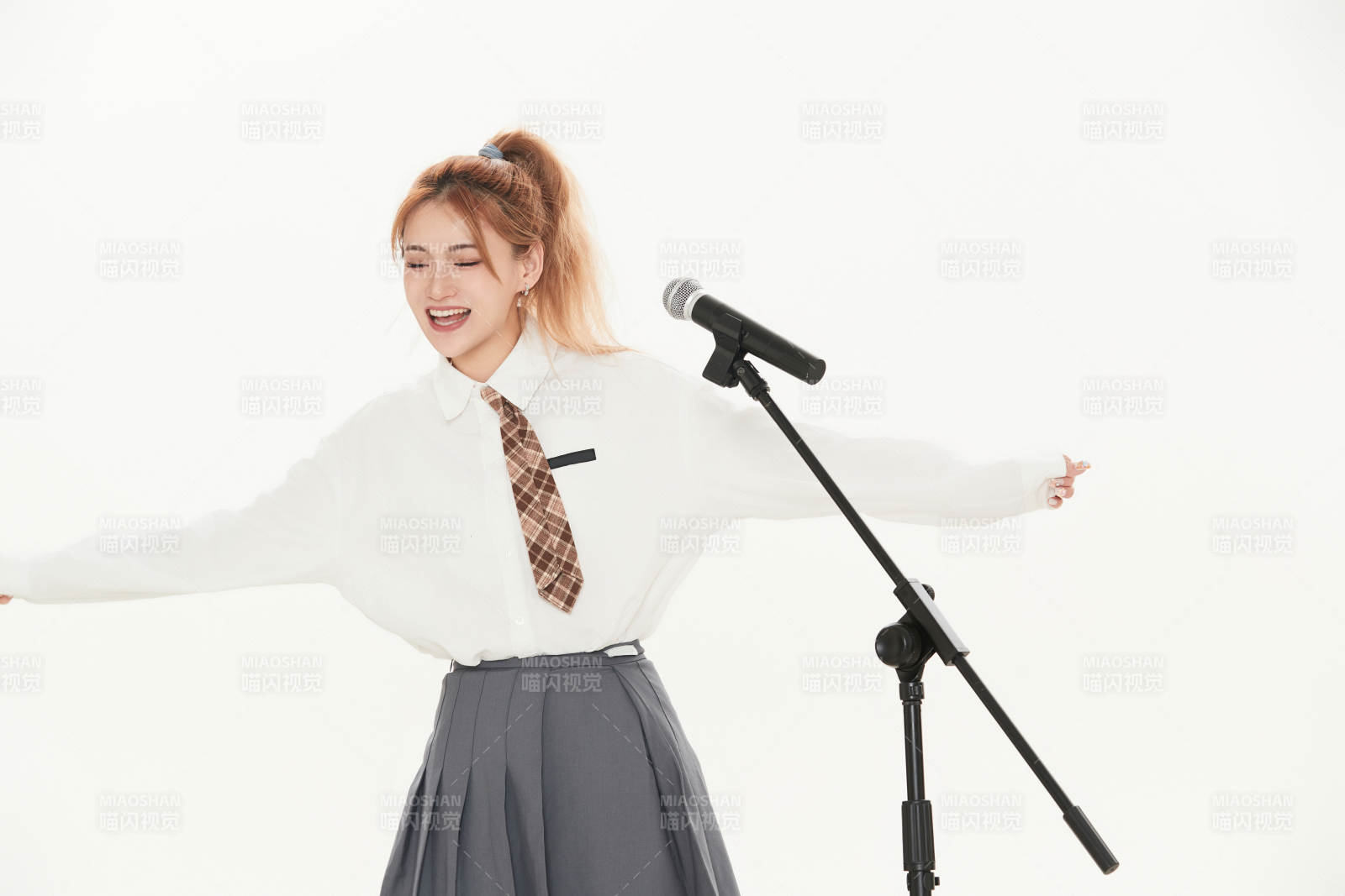 白色背景下站在麦克风前唱歌的亚洲女性