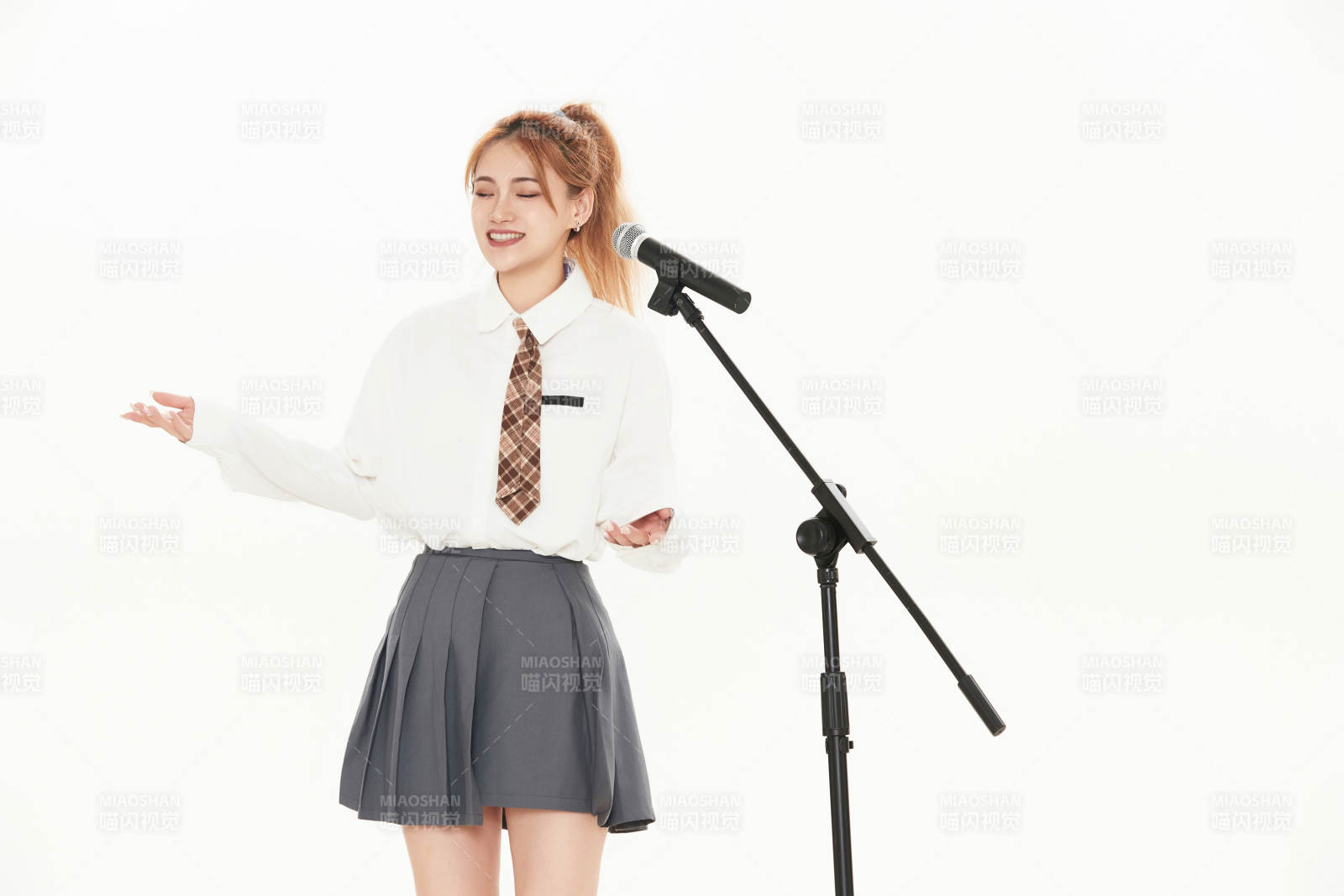 白色背景下站在麥克風前唱歌的亞洲女性