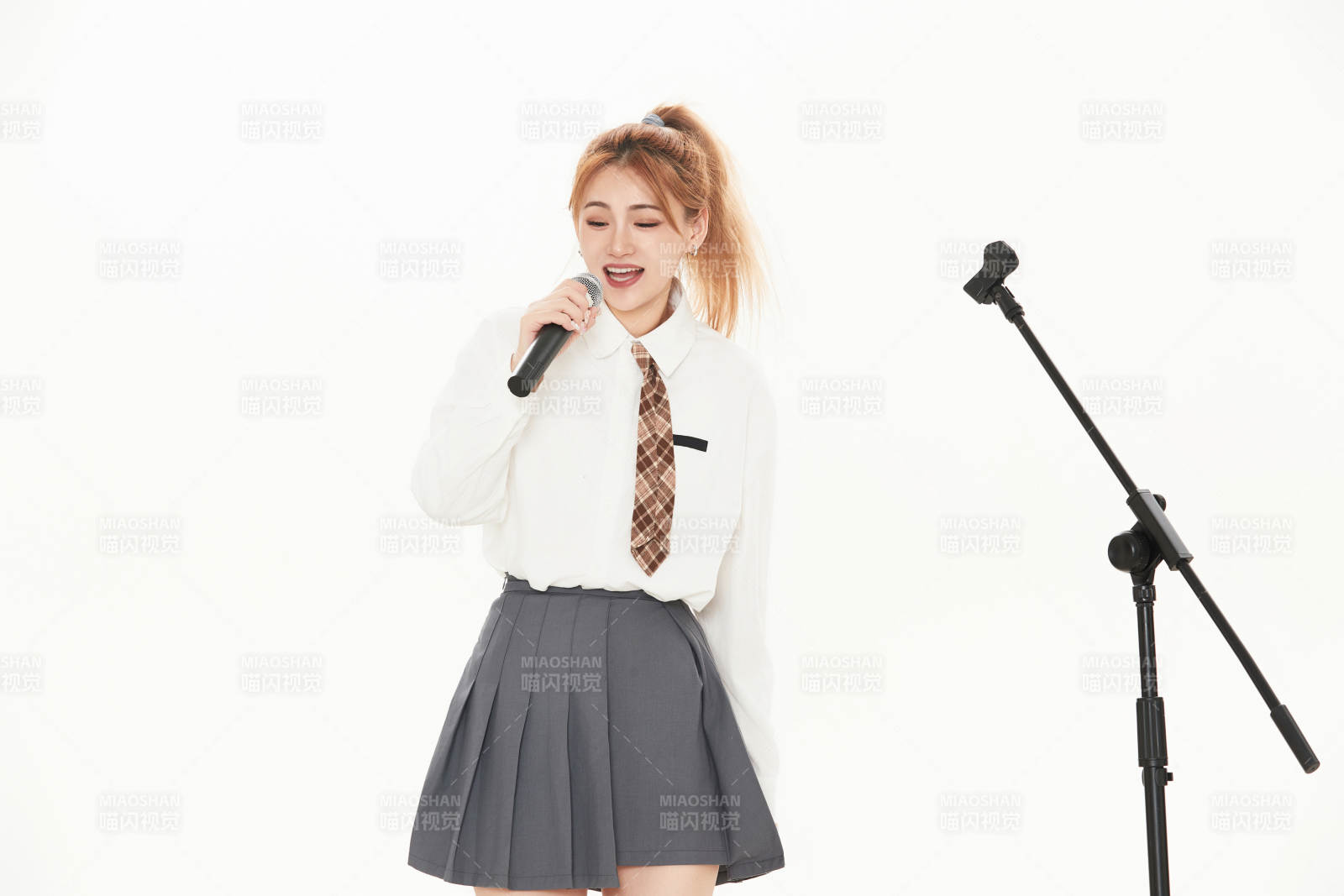 白色背景下站在麦克风前唱歌的亚洲女性