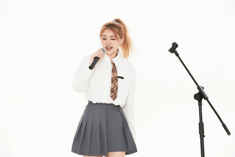 白色背景下站在麦克风前唱歌的亚洲女性