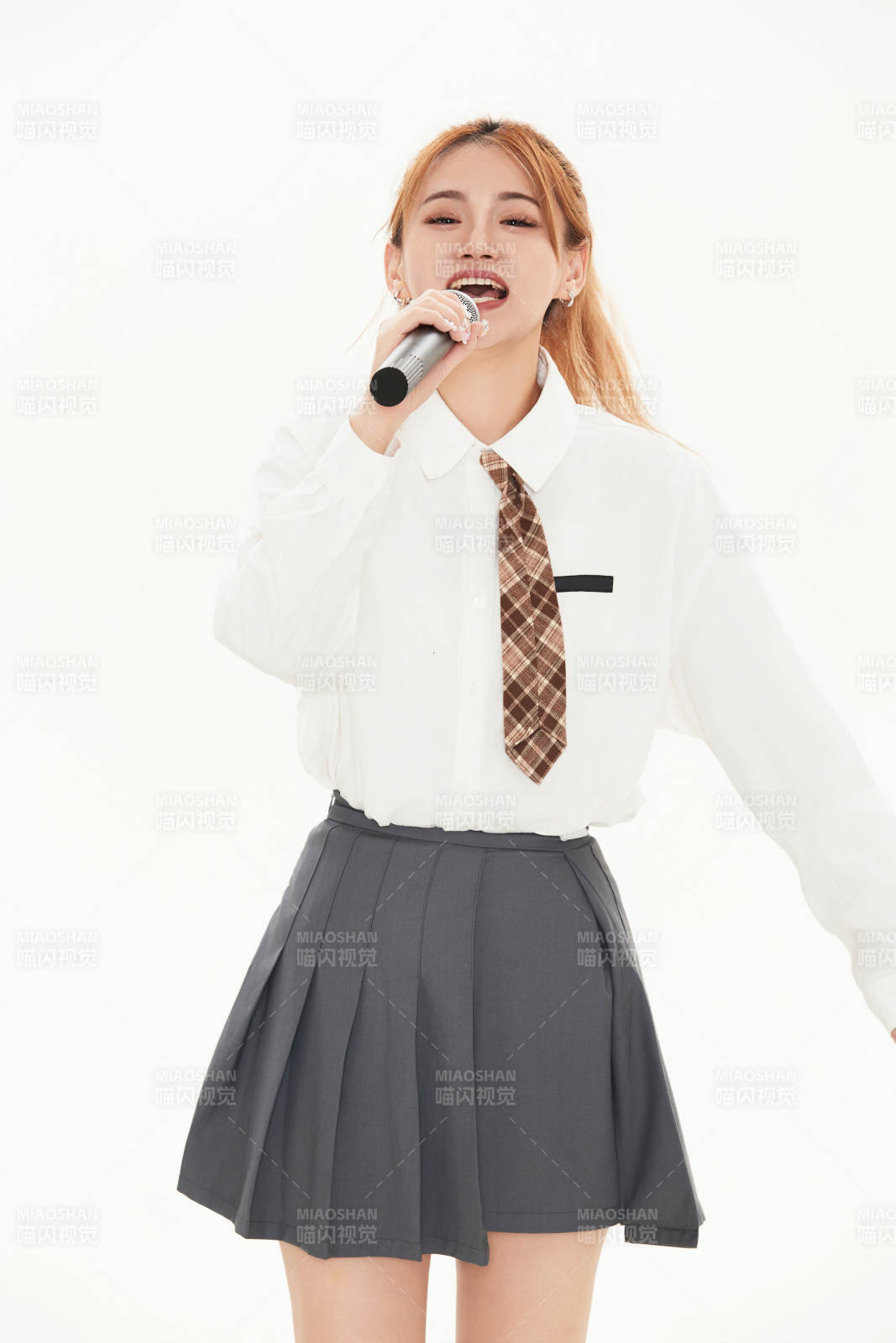 白色背景下站在麥克風前唱歌的亞洲女性