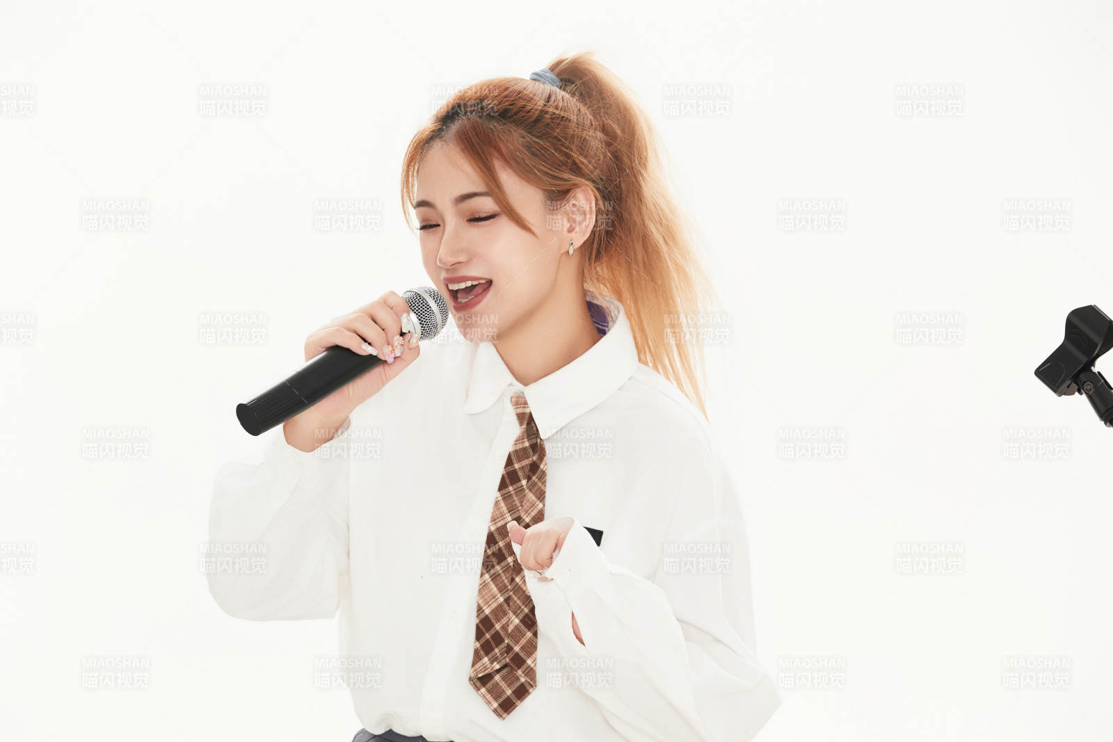 白色背景下站在麦克风前唱歌的亚洲女性