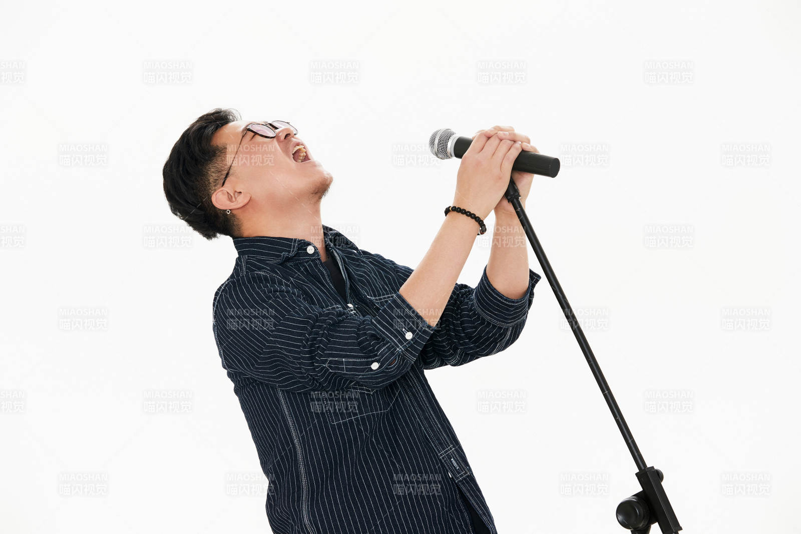 白色背景下站在麦克风前唱歌的亚洲男性
