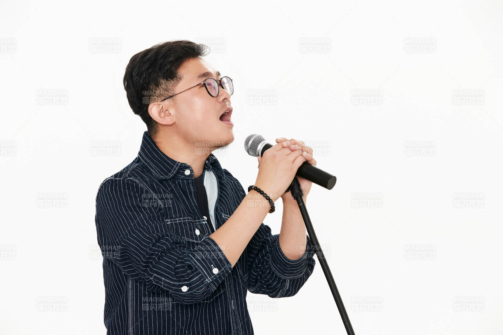 白色背景下站在麦克风前唱歌的亚洲男性