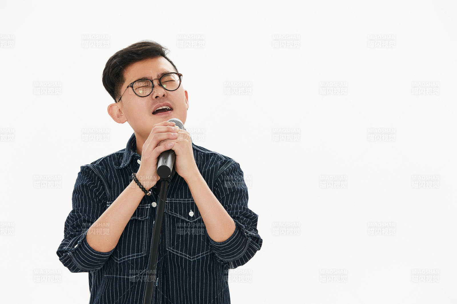 白色背景下站在麦克风前唱歌的亚洲男性