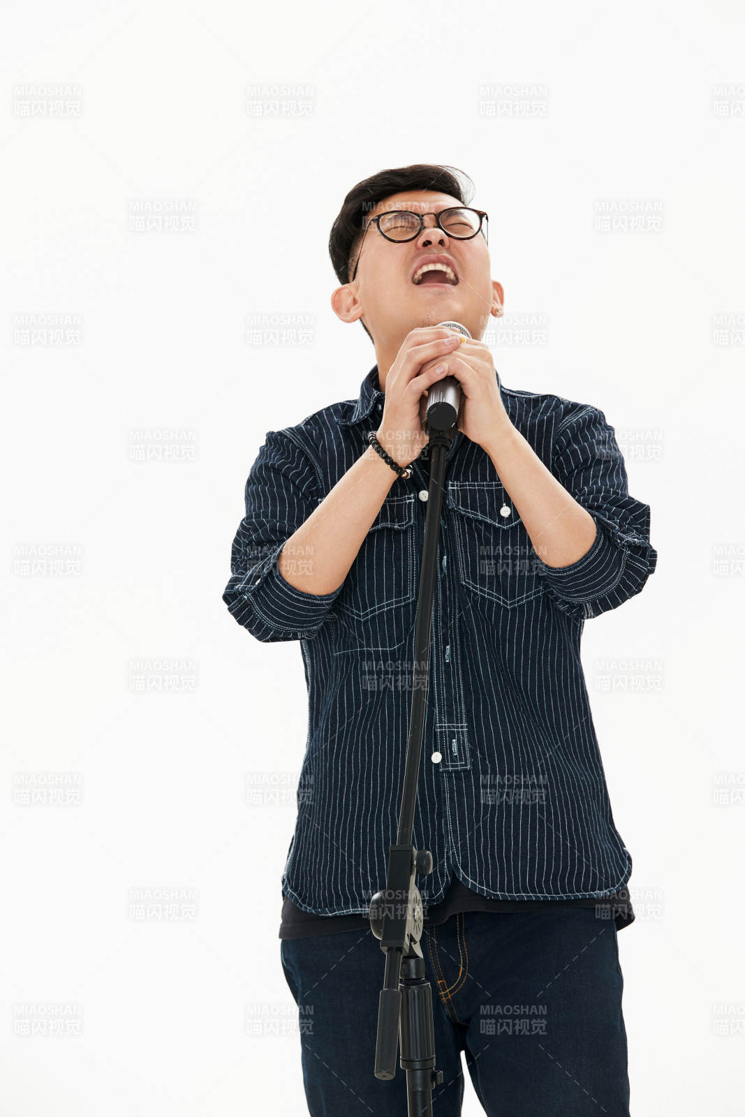 白色背景下站在麦克风前唱歌的亚洲男性