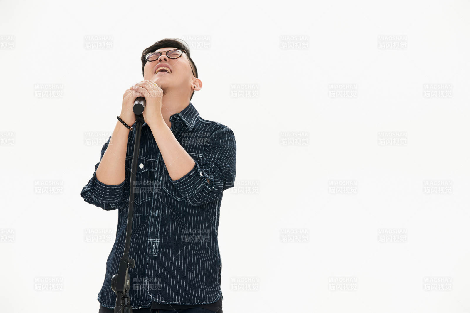 白色背景下站在麦克风前唱歌的亚洲男性