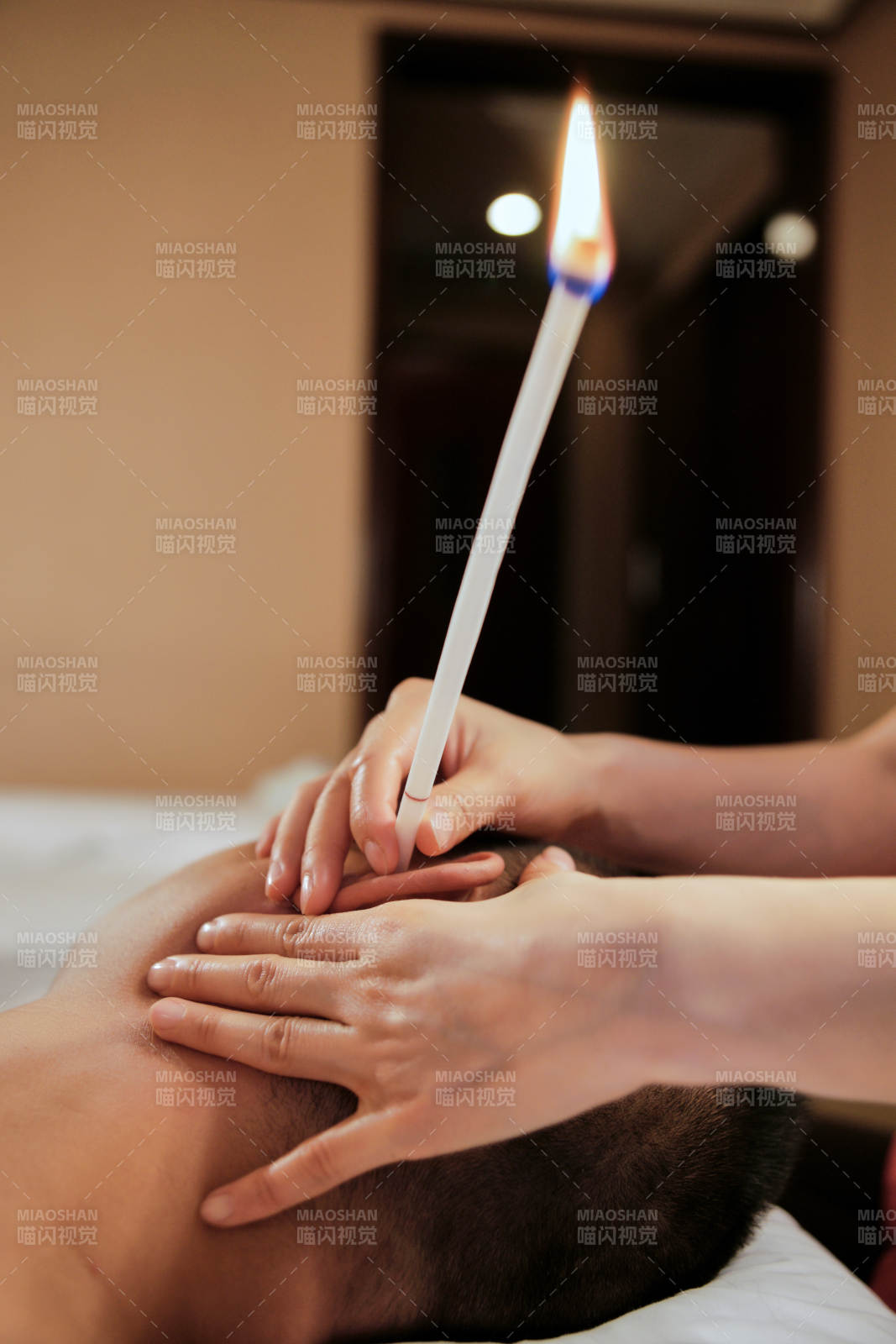 专业的按摩技师为顾客进行头部按摩及耳烛