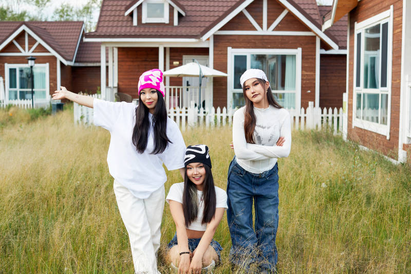 在旅游景区民宿外游玩拍照的三个姑娘们