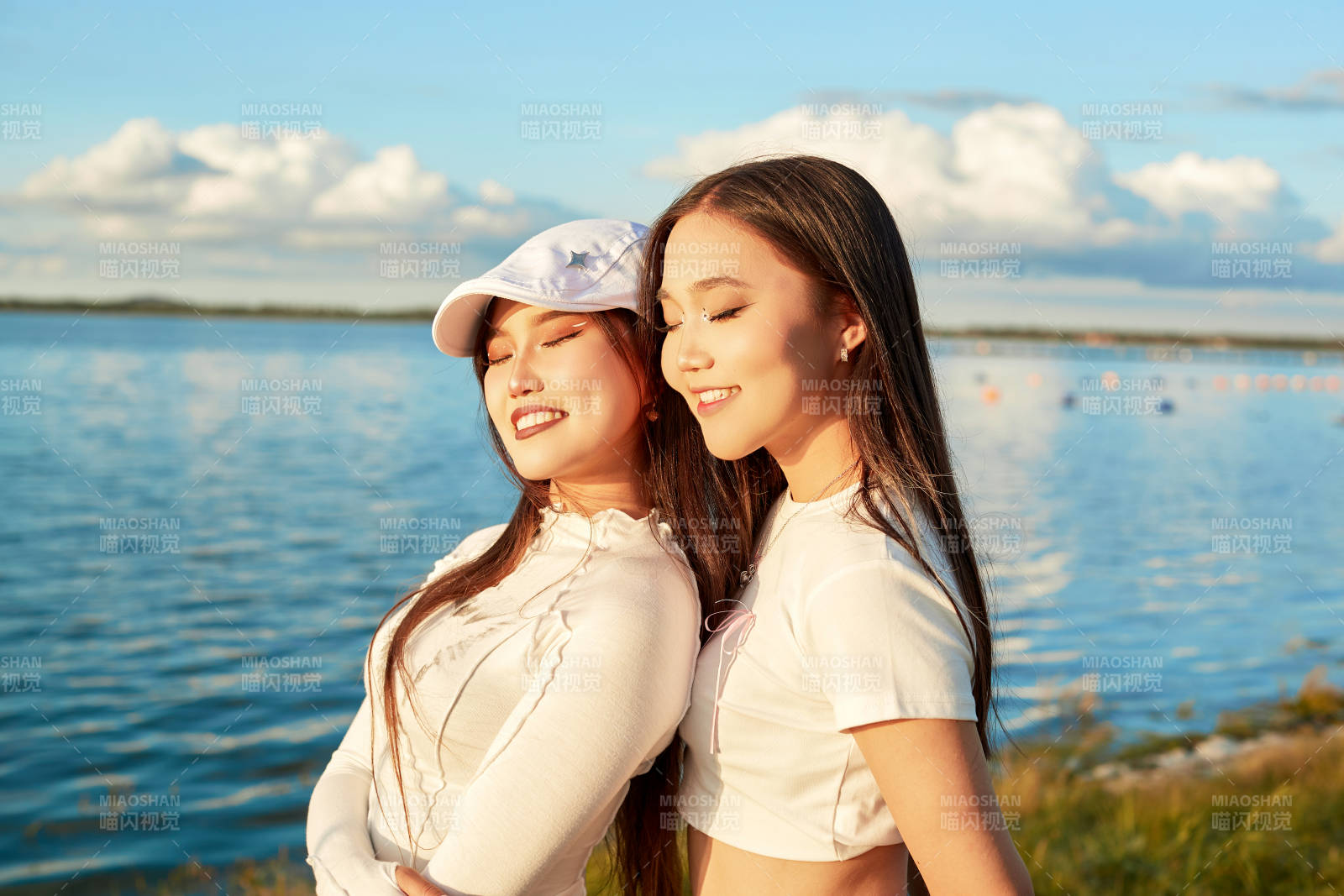 在旅游区湖边打卡点拍照的美女闺蜜