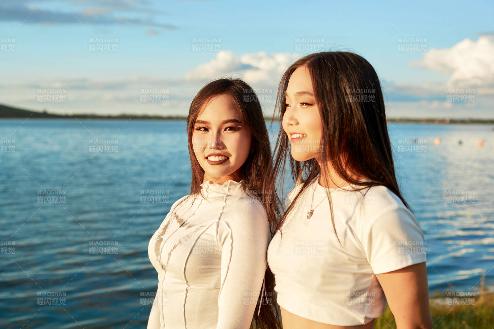 在旅游区湖边打卡点拍照的美女闺蜜