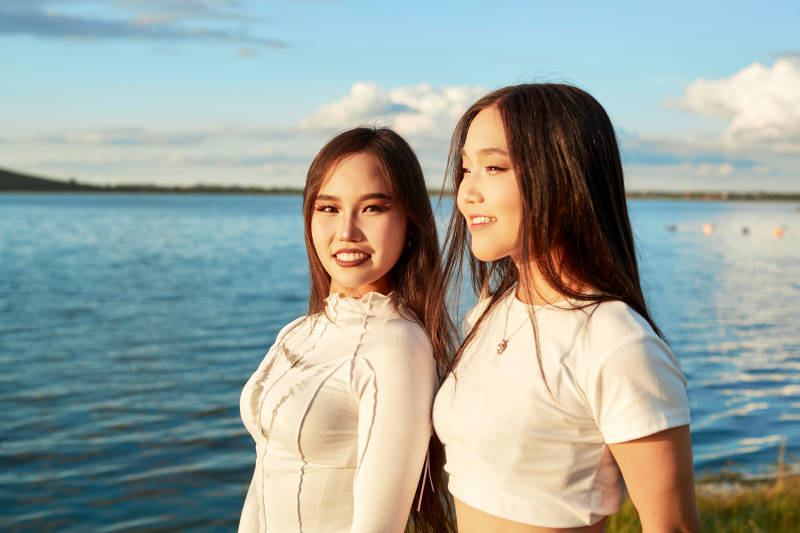 在旅游区湖边打卡点拍照的美女闺蜜