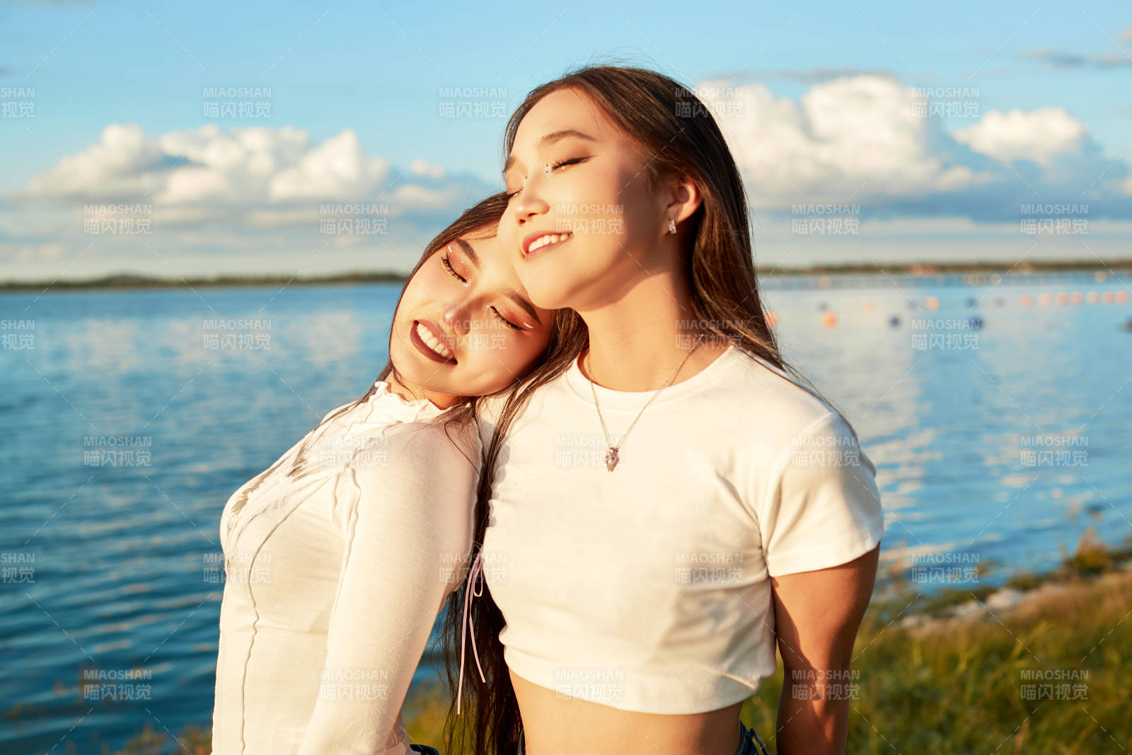 在旅游区湖边打卡点拍照的美女闺蜜