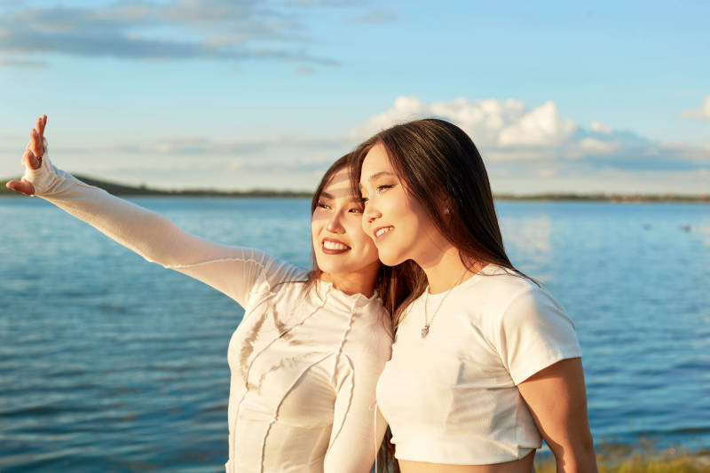 在旅游区湖边打卡点拍照的美女闺蜜