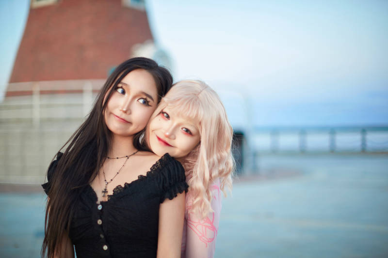 在旅游区湖边打卡点拍照的美女闺蜜