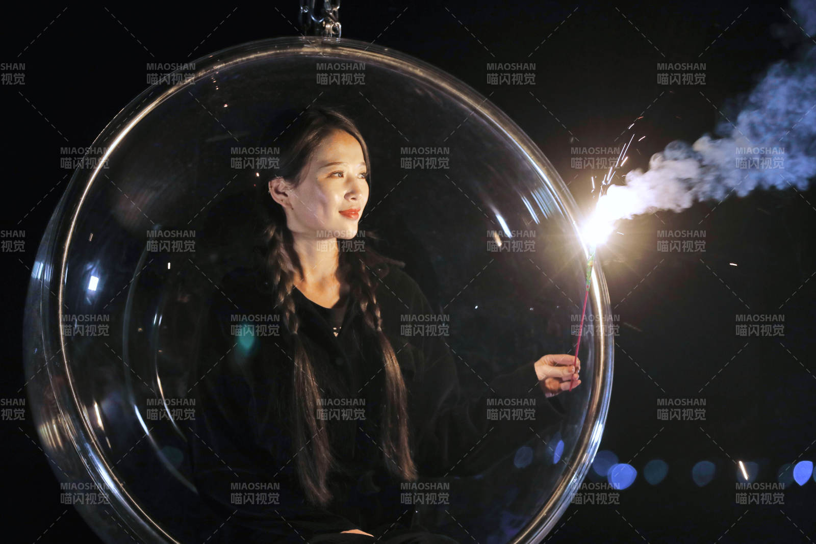 夜晚坐在透明秋千上燃放仙女棒的可爱少女