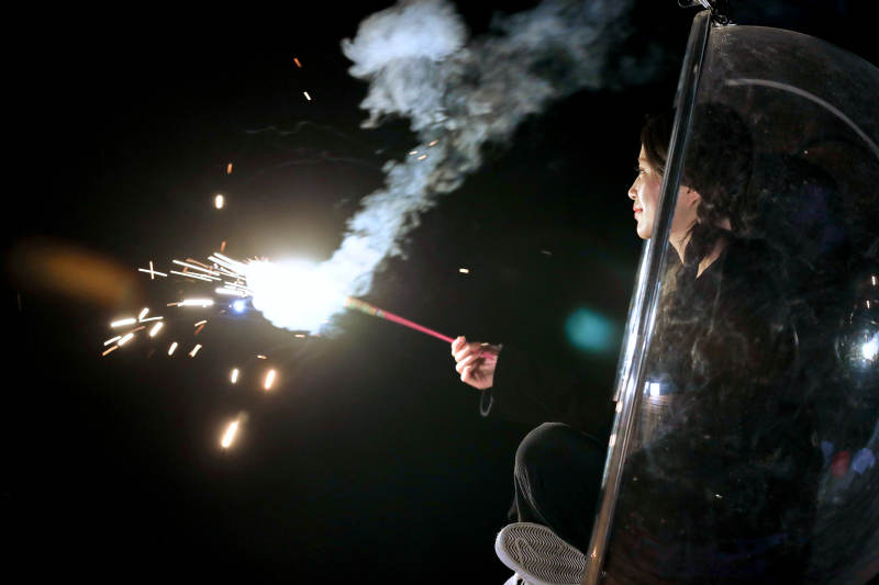 夜晚坐在透明秋千上燃放仙女棒的可爱少女