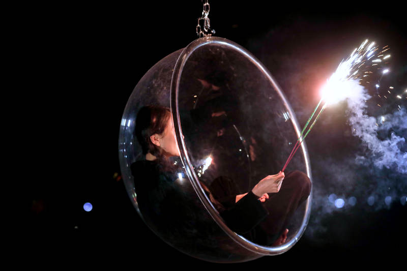 夜晚坐在透明秋千上燃放仙女棒的可爱少女