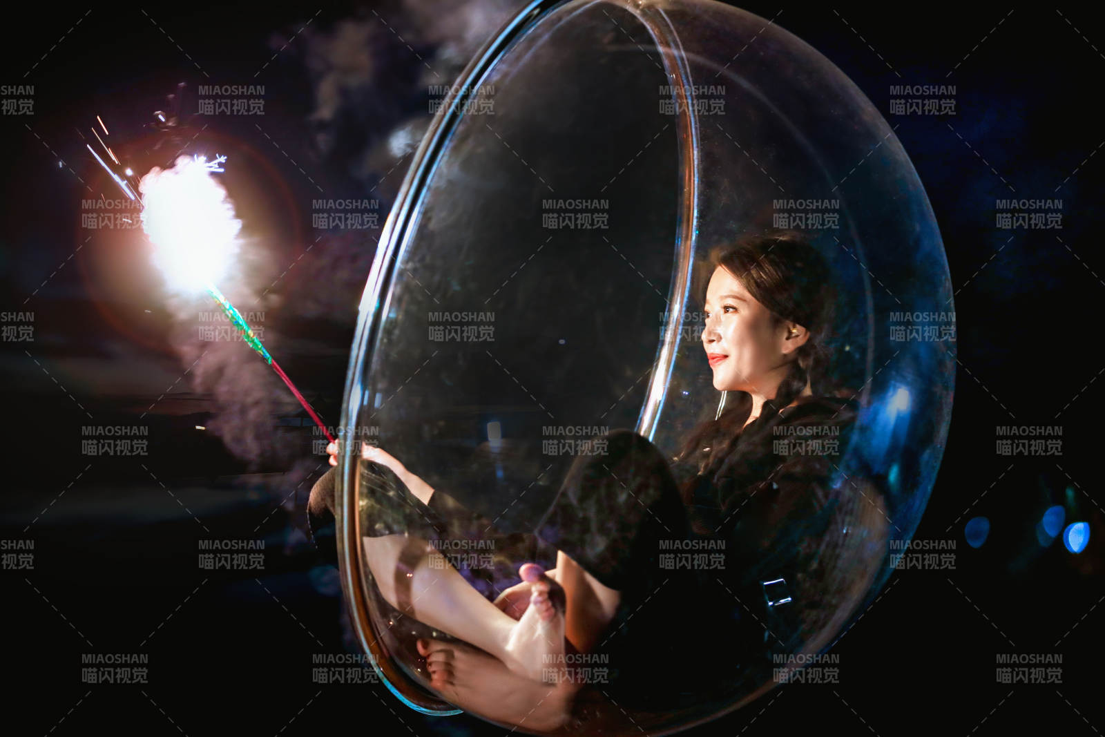 夜晚坐在透明秋千上燃放仙女棒的可爱少女