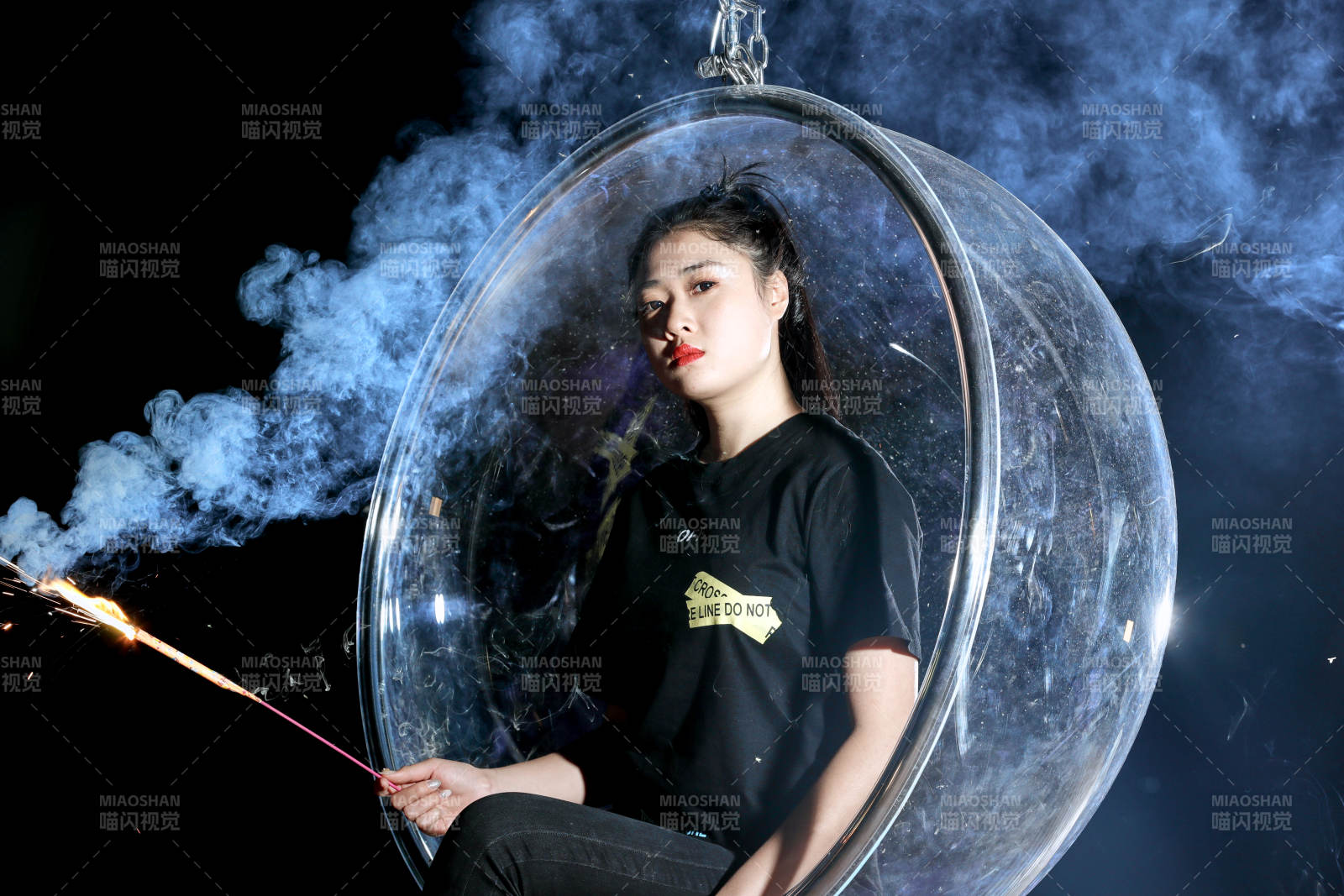 夜晚坐在透明秋千上燃放仙女棒的可爱少女