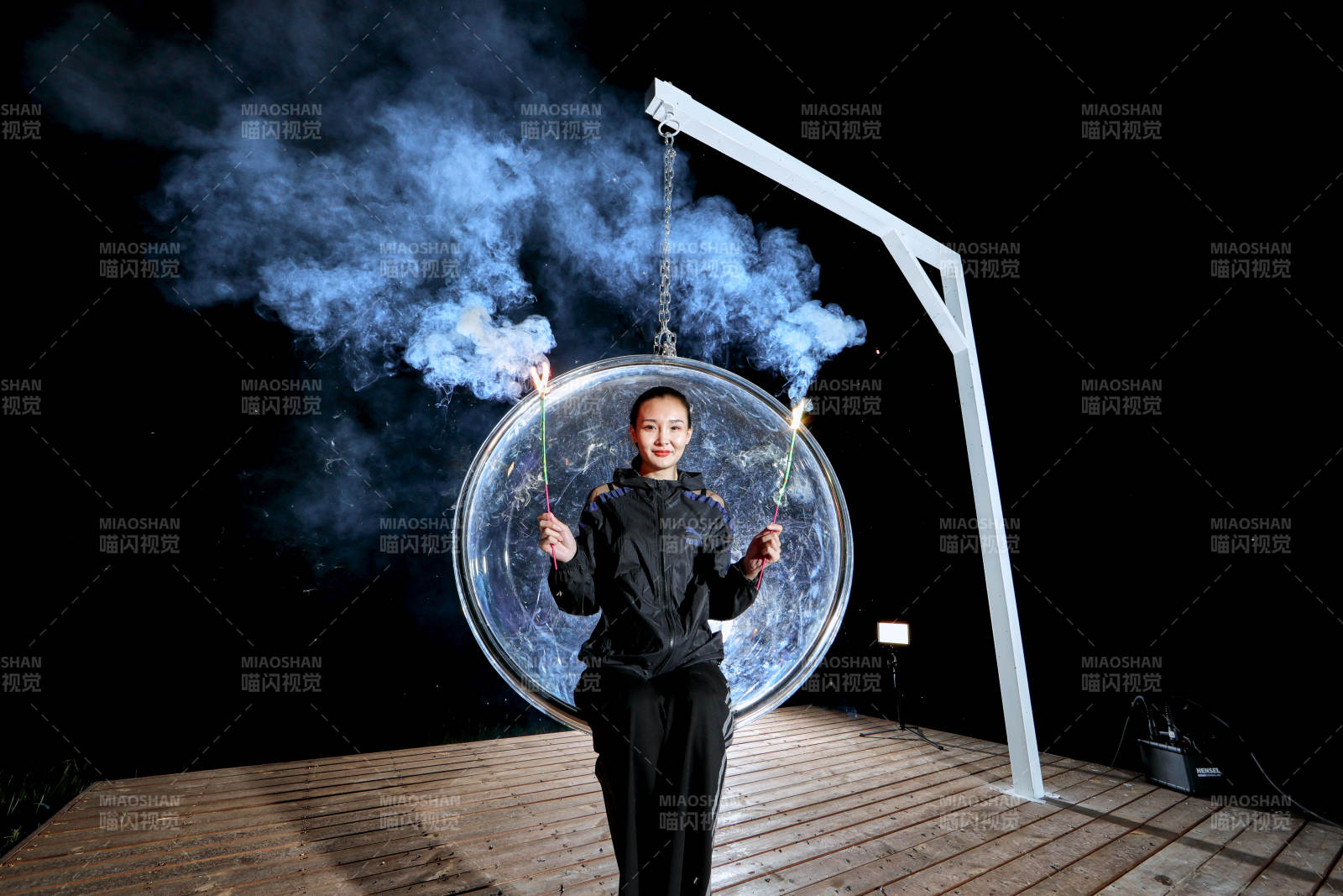 夜晚坐在透明秋千上燃放仙女棒的可爱少女