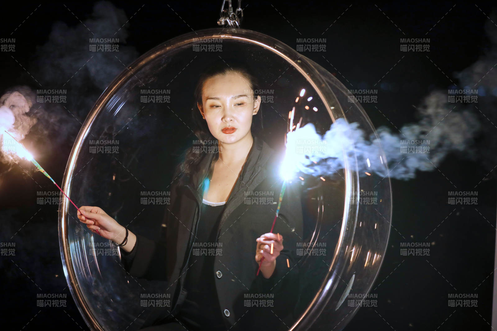 夜晚坐在透明秋千上燃放仙女棒的可愛少女