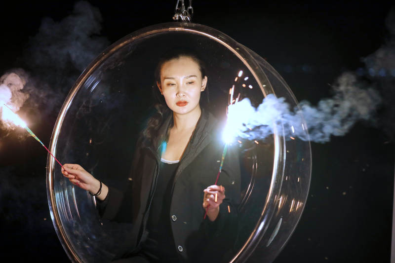 夜晚坐在透明秋千上燃放仙女棒的可爱少女